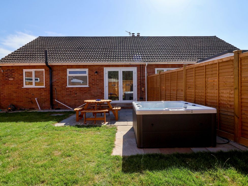 A garden with a hot tub and patio table at 1 Ashcott Place Burnham-On-Sea
