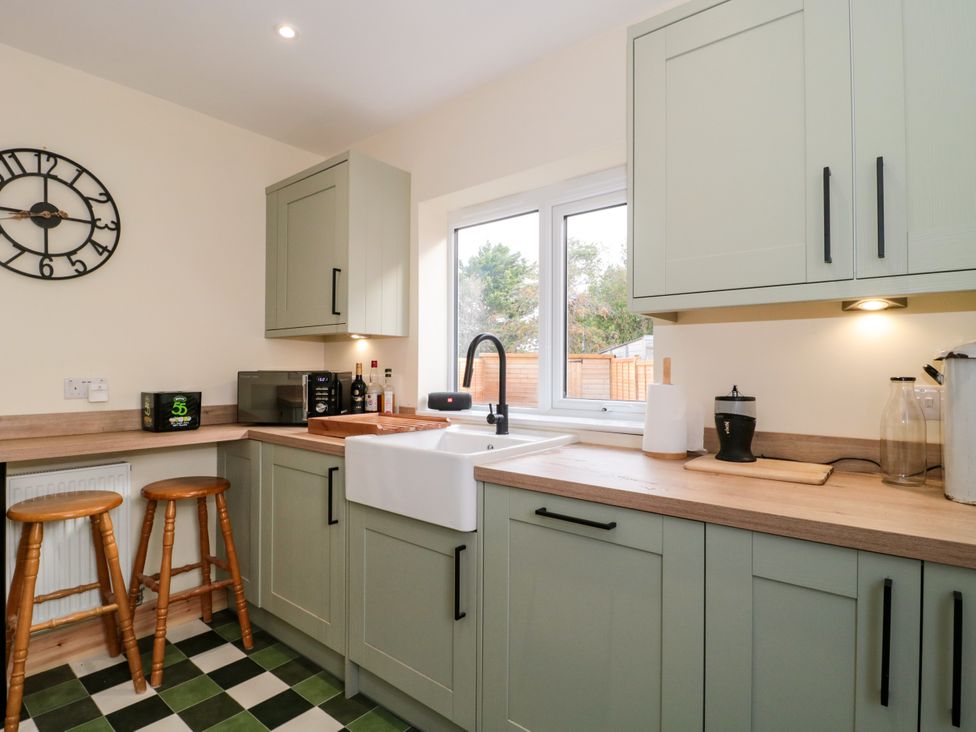 A kitchen with cabinets, sink, microwave and bar stools at 1 Ashcott Place Burnham-On-Sea
