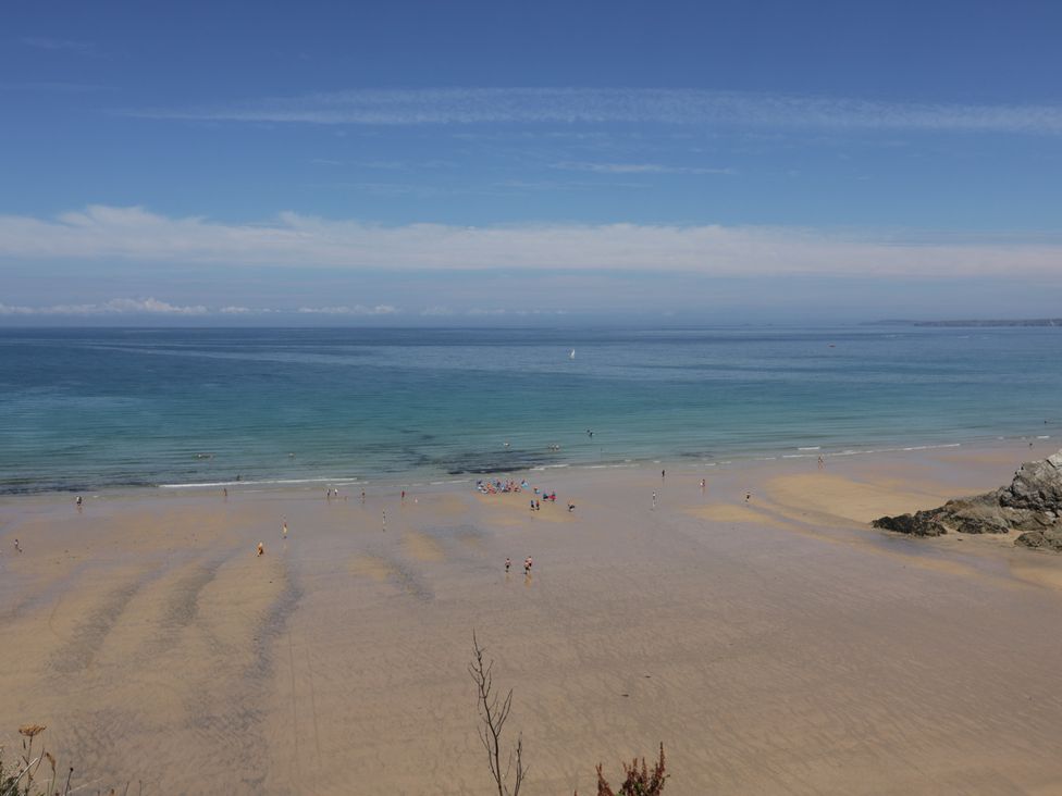 A beach with people walking near the water at Sea Snug in Newquay