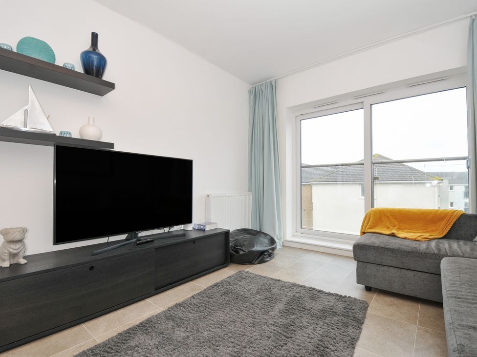 A living room with a television, shelf, and sofa at Sea Snug in Newquay