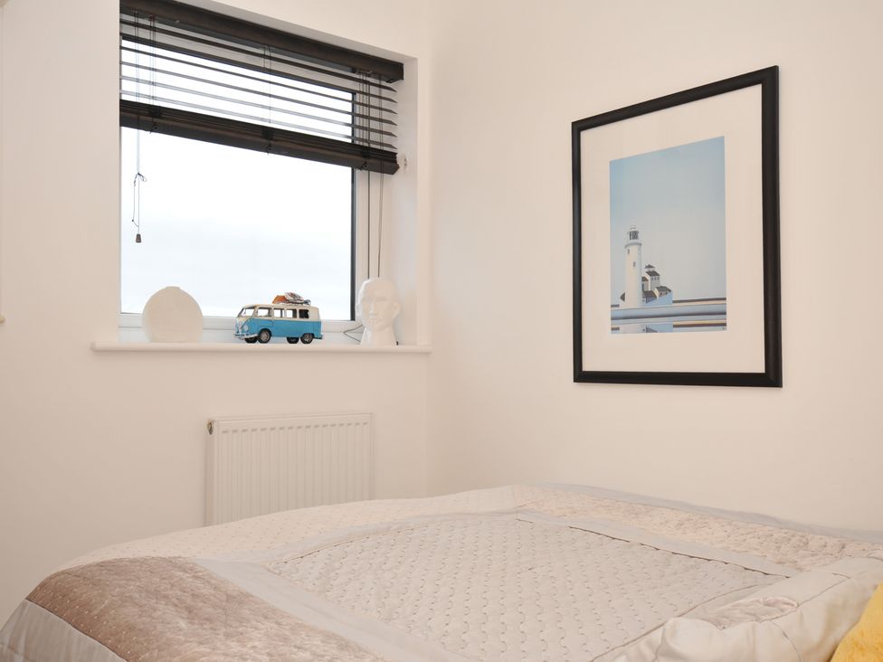 A bedroom with a window and framed picture at Sea Snug in Newquay