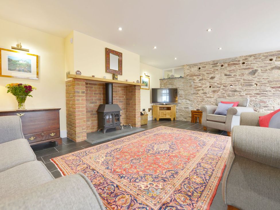 A living room with a fireplace and television at The Cider Barn at Home Farm Down Thomas near Wembury