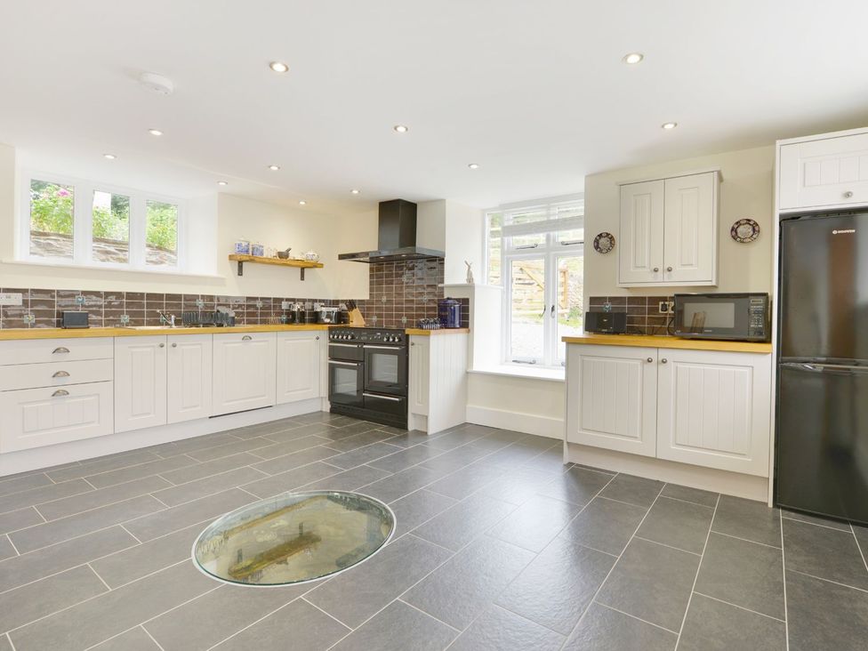 A kitchen with cabinets, a cooker, and a sink at The Cider Barn at Home Farm Down Thomas near Wembury