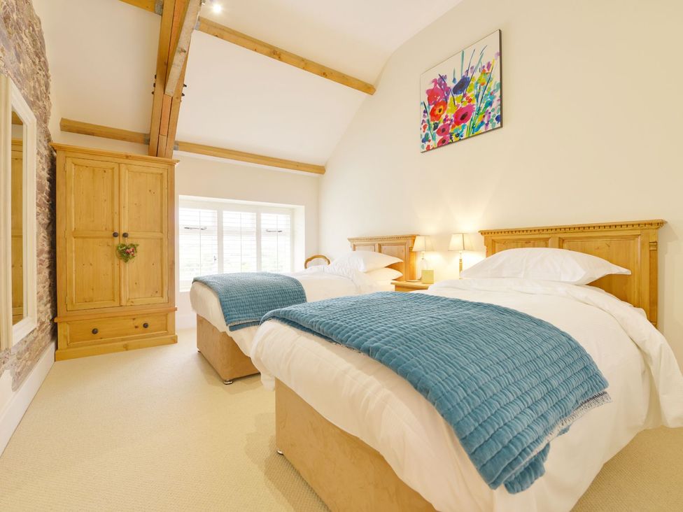 A bedroom with two beds and a wardrobe at The Cider Barn at Home Farm Down Thomas near Wembury