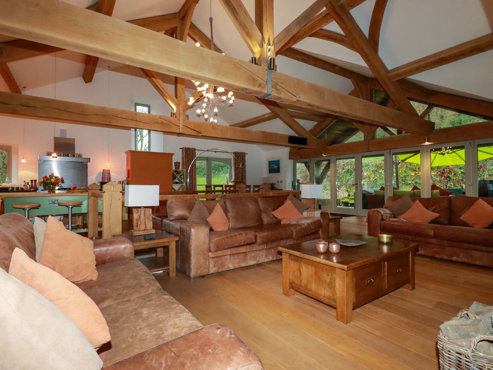 A living room with sofas, a coffee table, and a kitchen area at Kerslake House in Crafthole