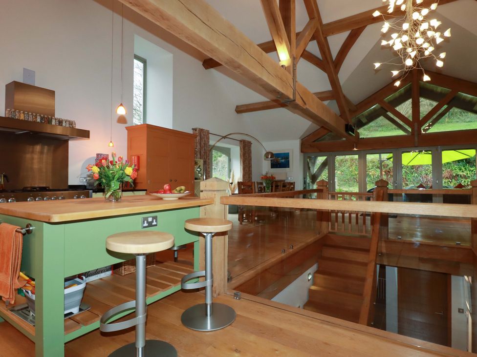 A kitchen with a green island and wooden beams at Kerslake House in Crafthole