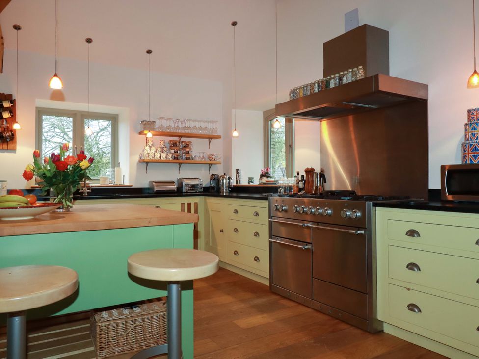 A kitchen with a stove, sink, and bar stools at Kerslake House in Crafthole