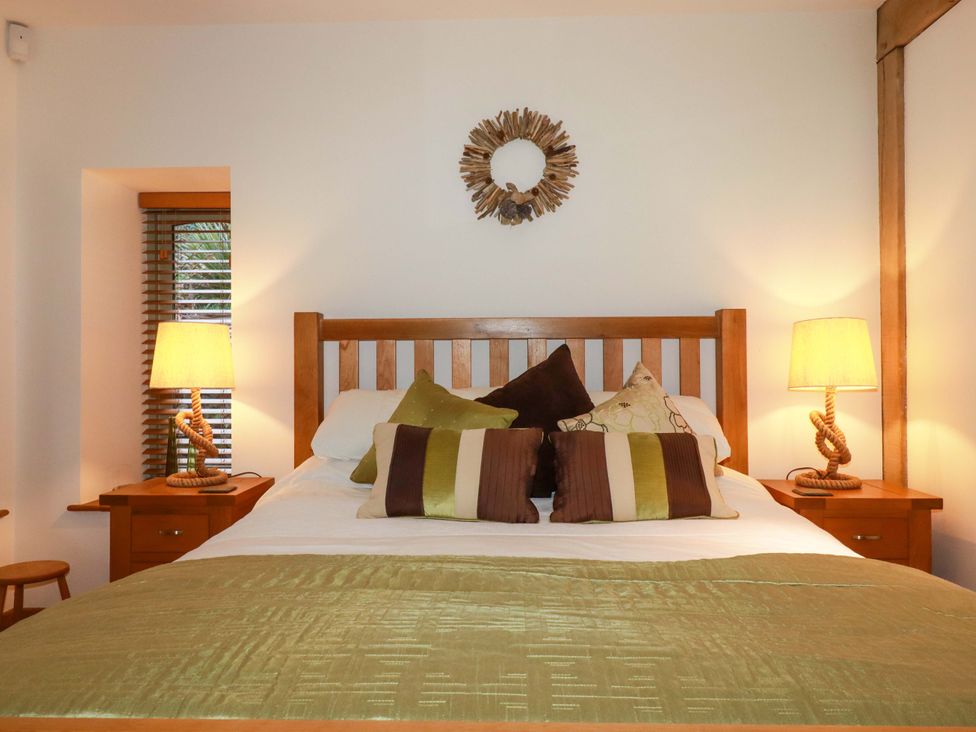 A bedroom with a wooden bed and bedside tables at Kerslake House Crafthole