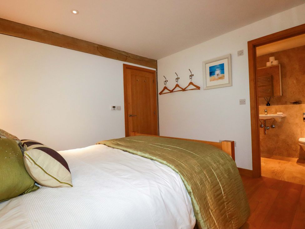 A bedroom with a bed and bathroom access at Kerslake House in Crafthole