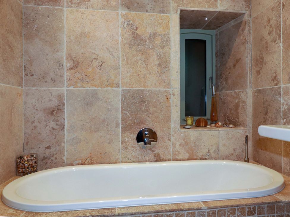 A bathroom with a bathtub and decorative items at Kerslake House Crafthole