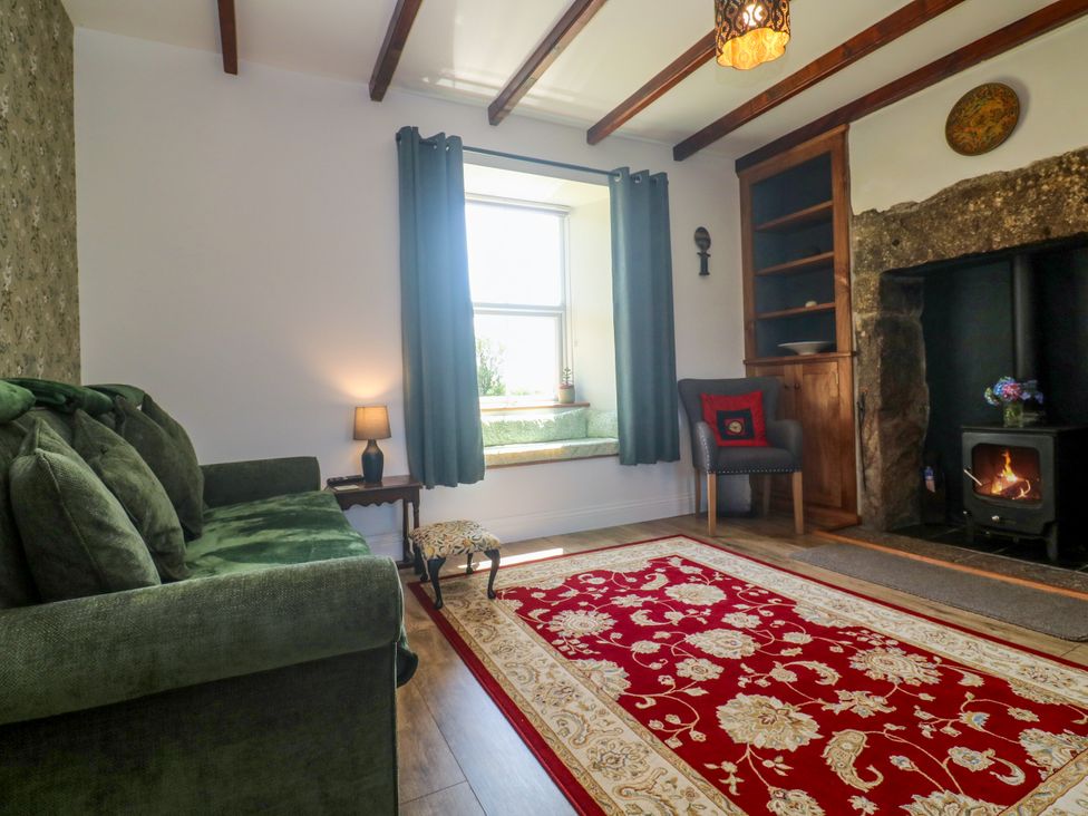 A living room with a sofa and wood stove at Halwyn Farm in Helston