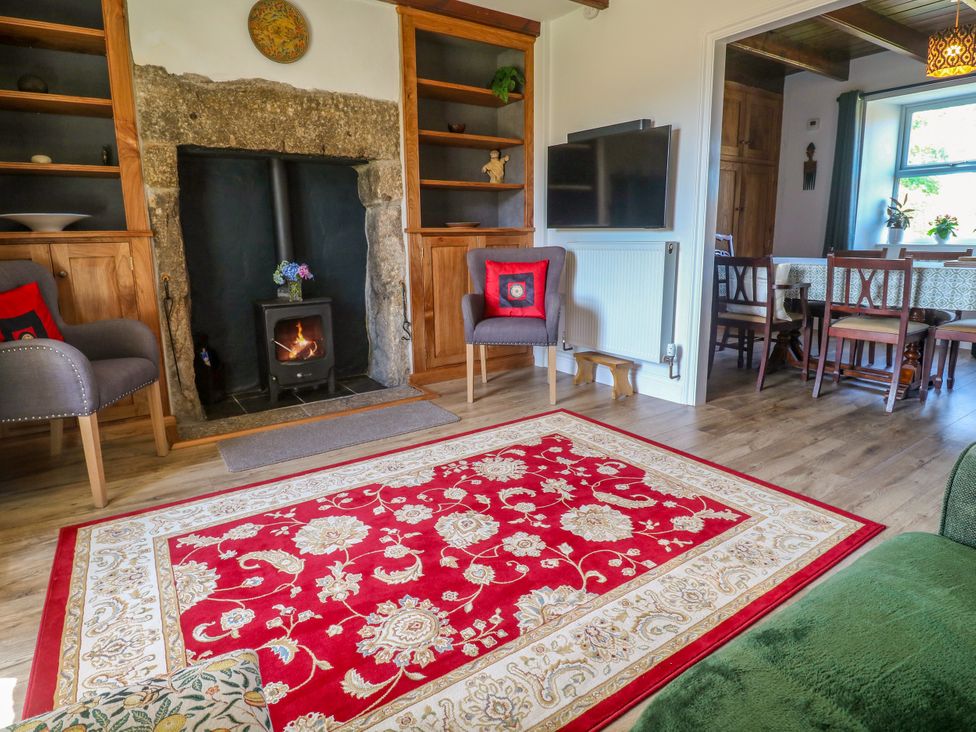 A living room with a wood stove and chairs at Halwyn Farm in Helston