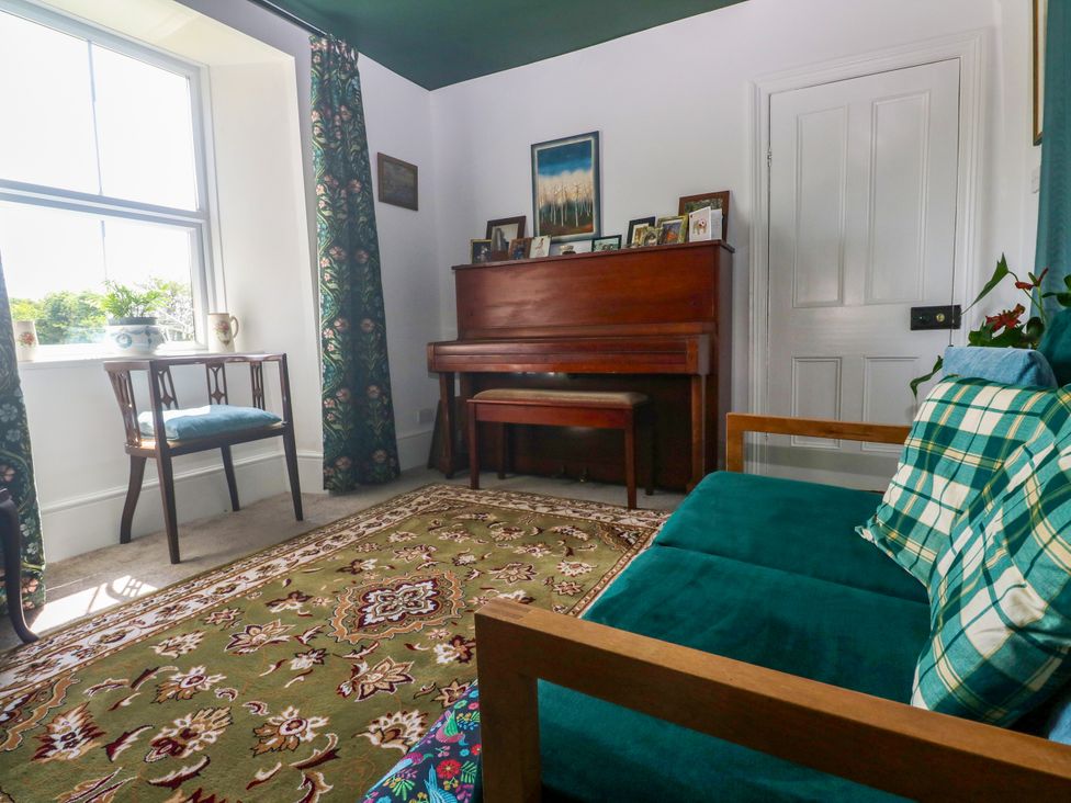 A snug with a piano and a chair at Halwyn Farm in Helston