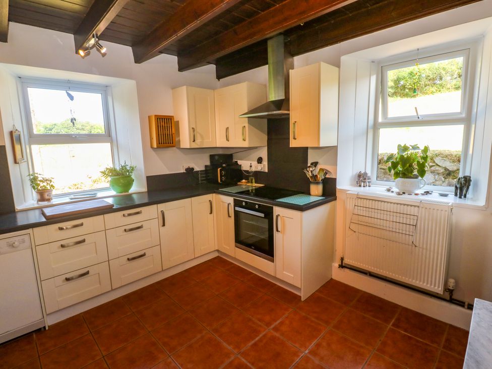 A kitchen with cabinets, oven, sink and windows at Halwyn Farm in Helston