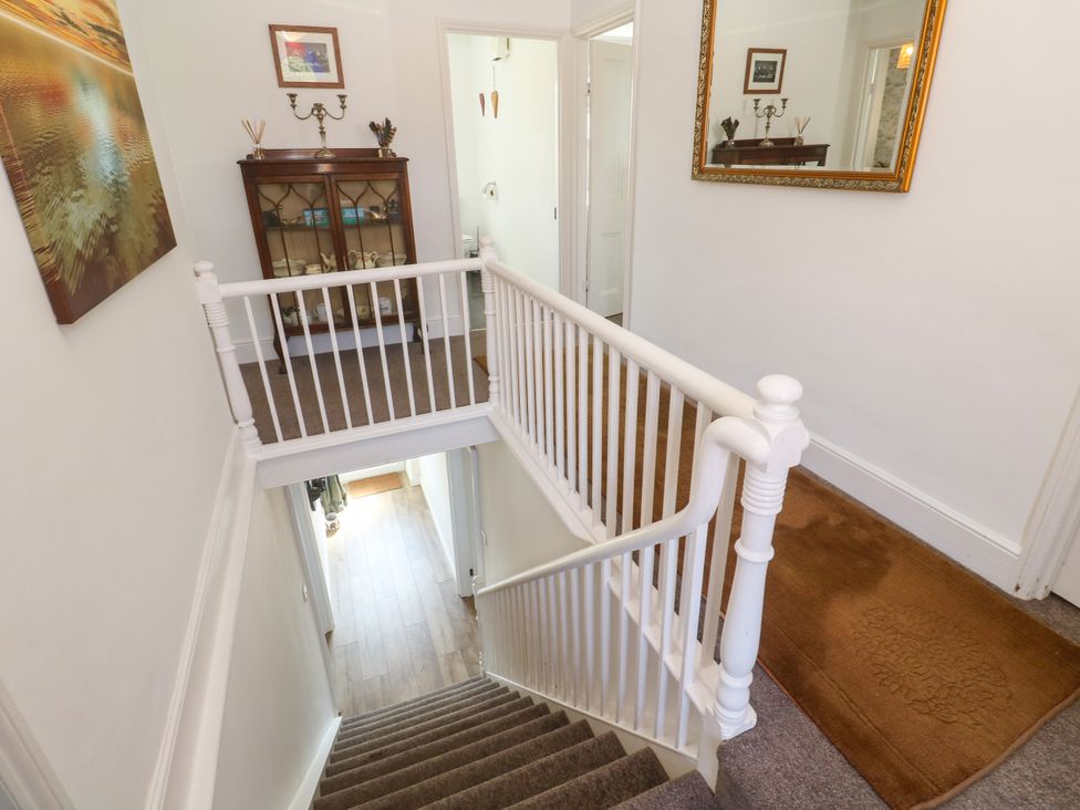 A hallway with a staircase and cabinet at Halwyn Farm in Helston