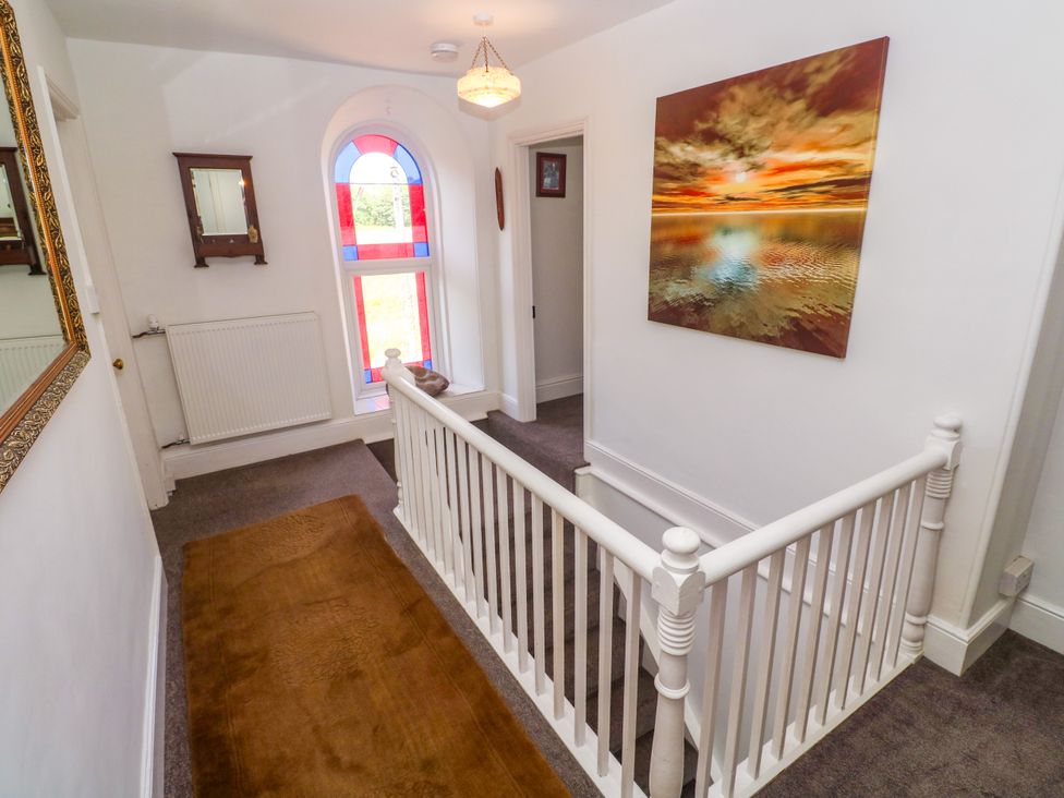 A hallway with a staircase and window at Halwyn Farm in Helston