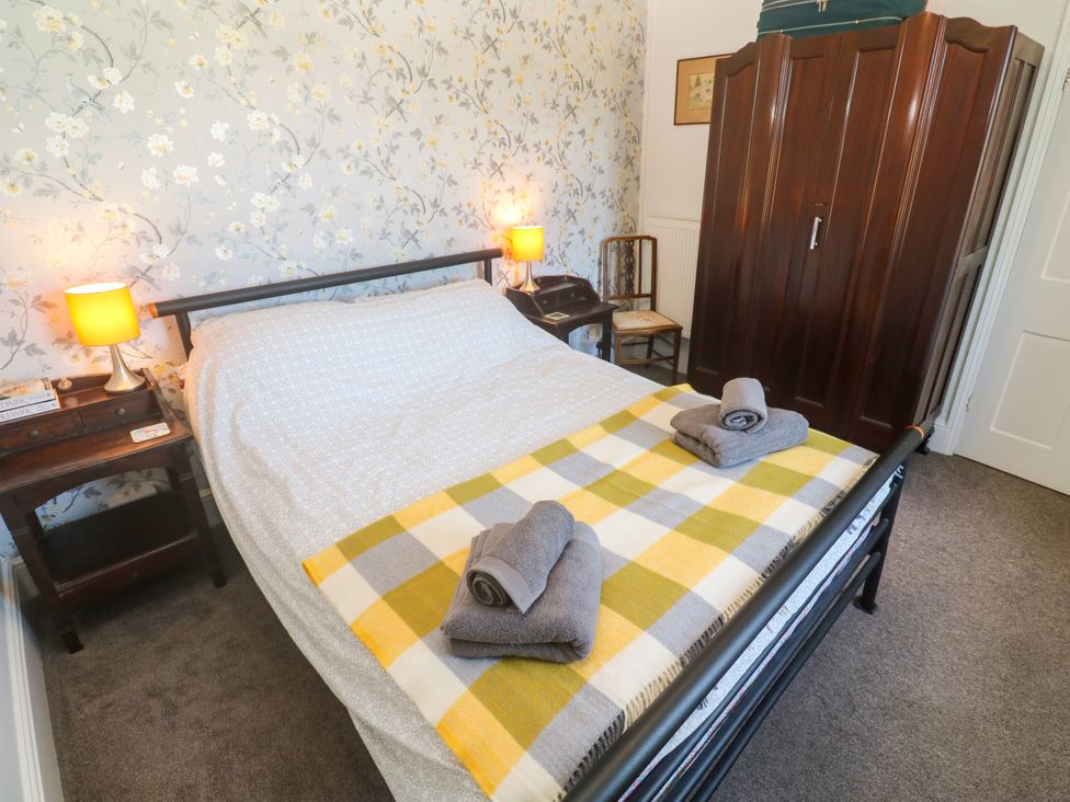 A bedroom with a bed, wardrobe, lamps, and towels at Halwyn Farm in Helston