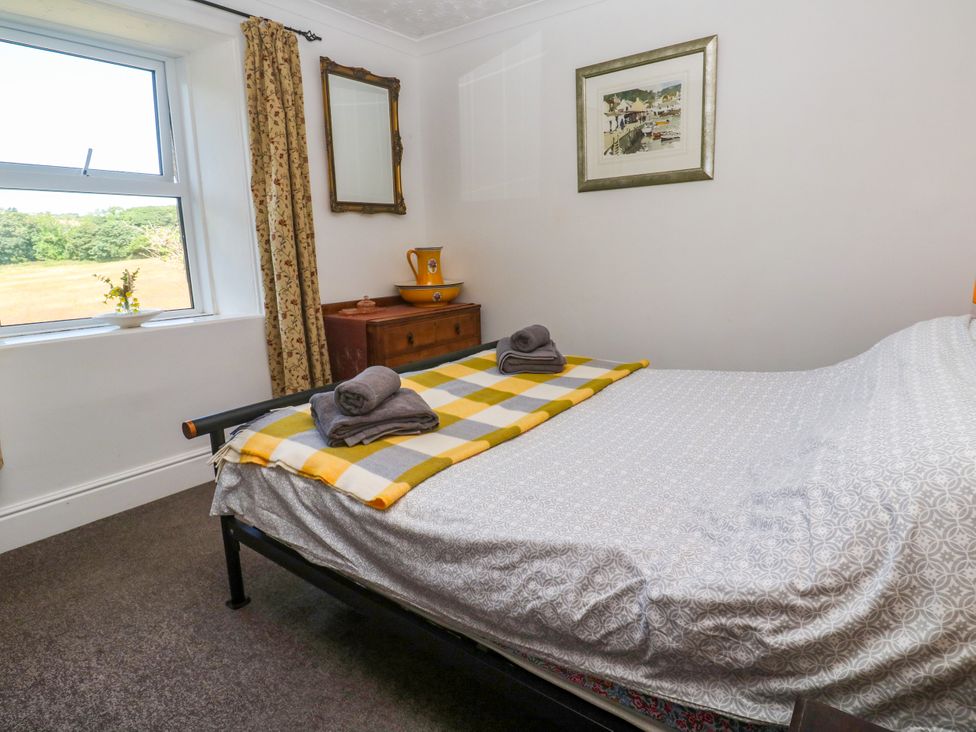 A bedroom with a bed and window at Halwyn Farm in Helston