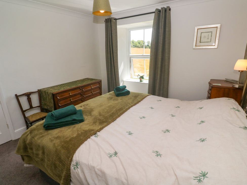 A bedroom with a bed and dressing table at Halwyn Farm in Helston