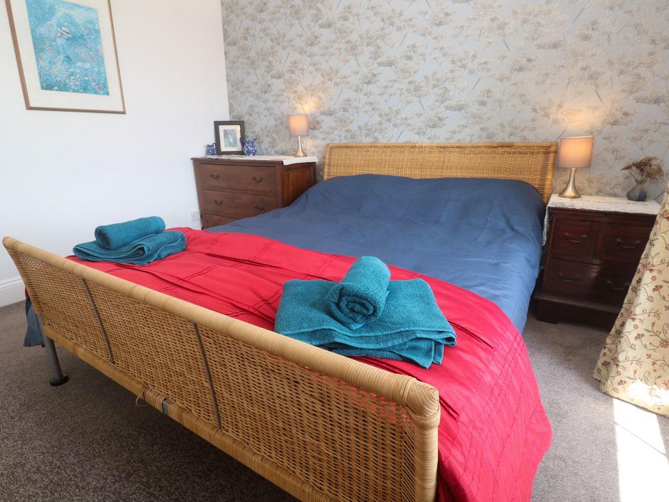 A bedroom with a bed, nightstand, lamp, and towels at Halwyn Farm in Helston