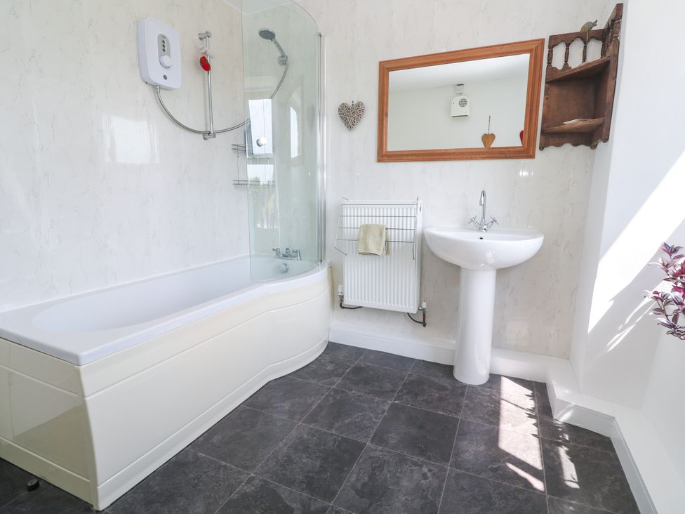 A bathroom with a bathtub, sink, and radiator at Halwyn Farm in Helston