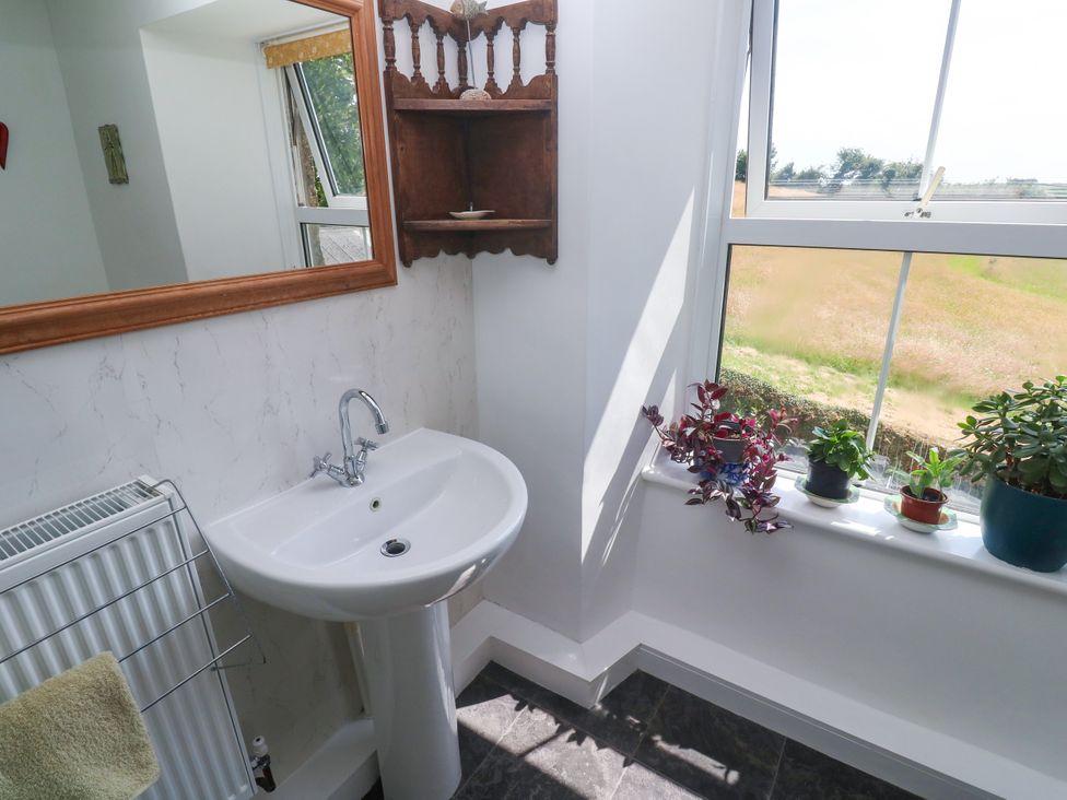 A bathroom with a sink and plants on a windowsill at Halwyn Farm in Helston