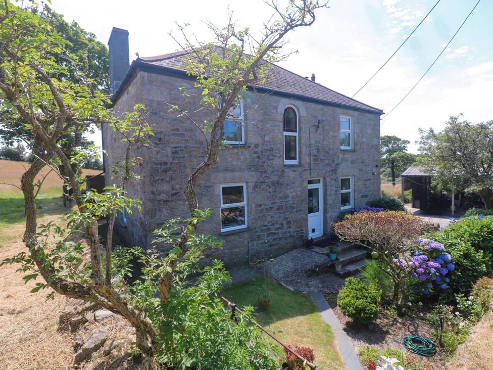 A stone house with garden plants and steps at Halwyn Farm in Helston