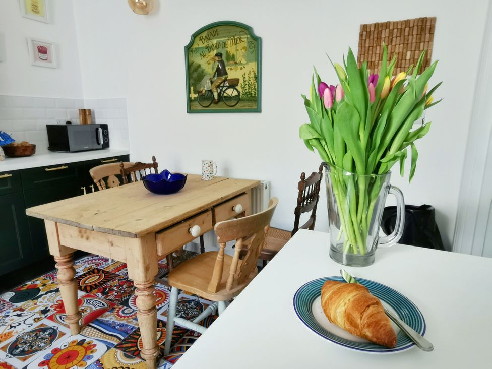 A kitchen with a table, chairs, vase of tulips and a croissant at 21 Gensing Road, St. Leonards-on-Sea