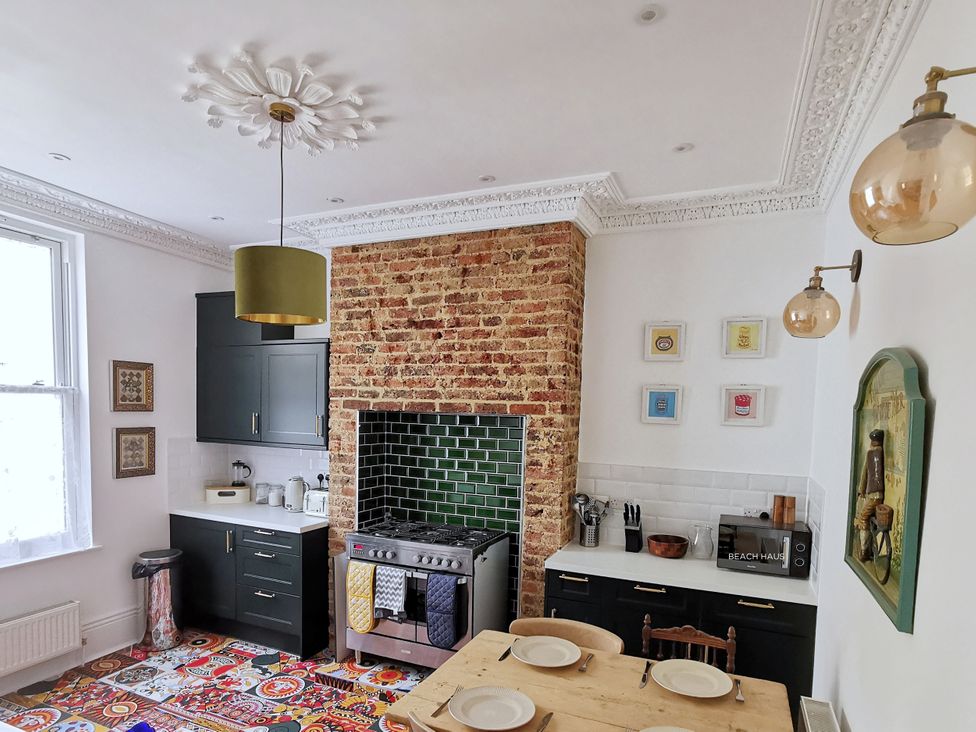 A kitchen with a stone wall, stove, and table at 21 Gensing Road in St. Leonards-on-Sea