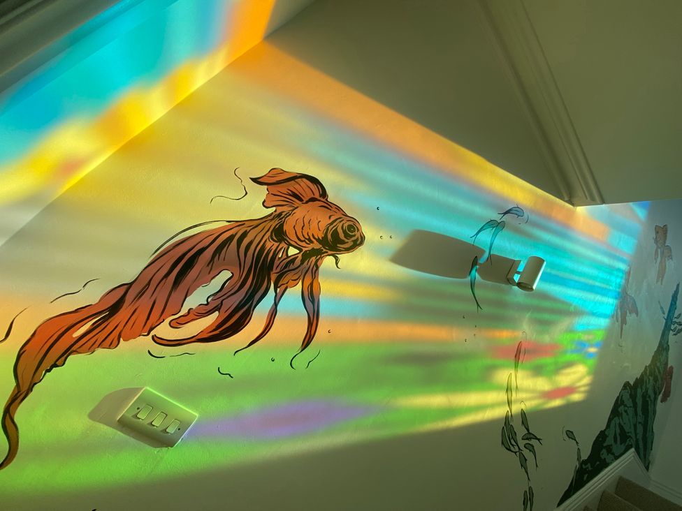 A wall with a fish mural and colorful light patterns at 21 Gensing Road St. Leonards-on-Sea