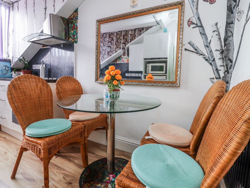 A dining room with a glass table and wicker chairs at Number 8 in Blackpool