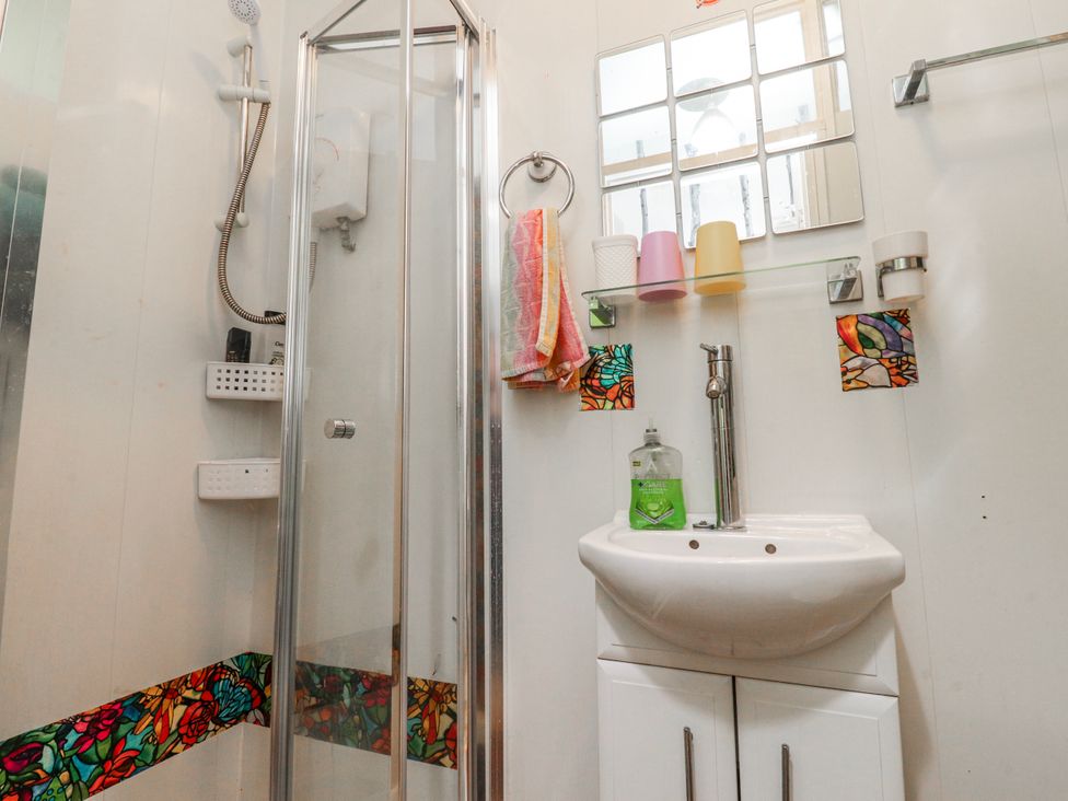 A bathroom with a shower, sink, and mirror at Number 8 Blackpool