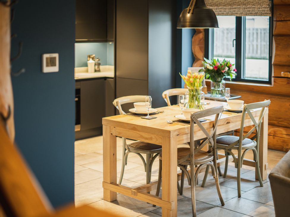 A dining area with wooden table and flowers at The Lookout in Addingham