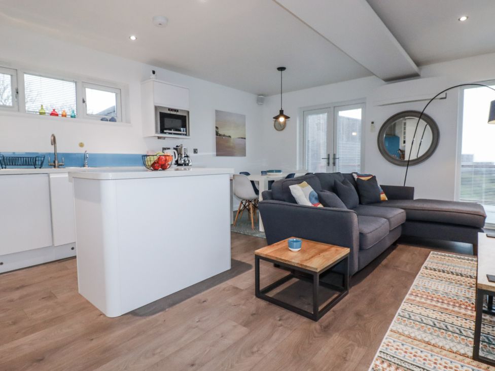 A living room with a sofa and kitchen island at Pentewan in Redruth