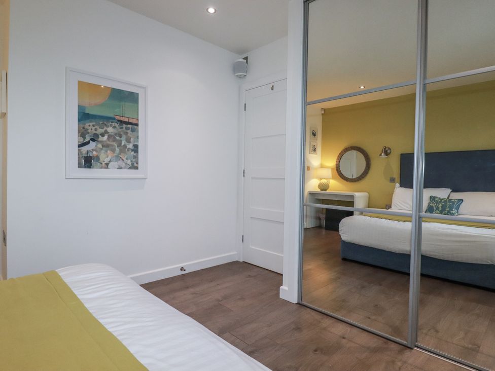 A bedroom with a bed and mirror at Pentewan in Redruth