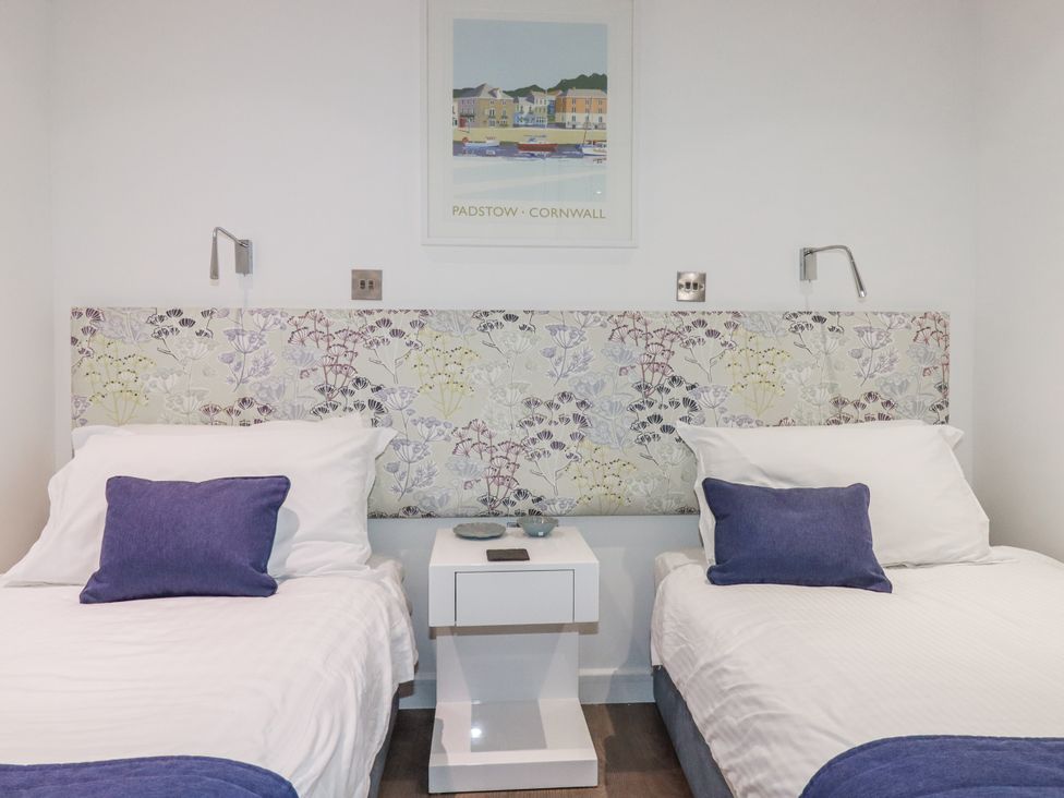 A bedroom with two beds and a bedside table at Pentewan in Redruth