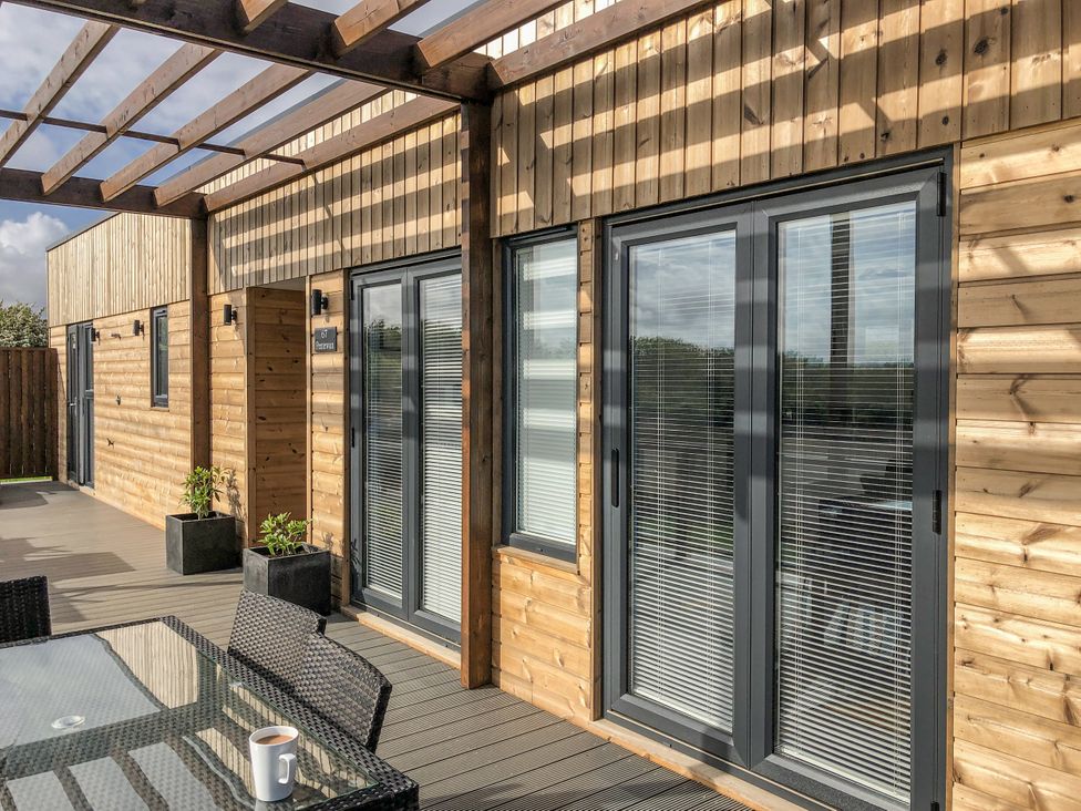 An outdoor seating area with sliding doors and a table at Pentewan in Redruth