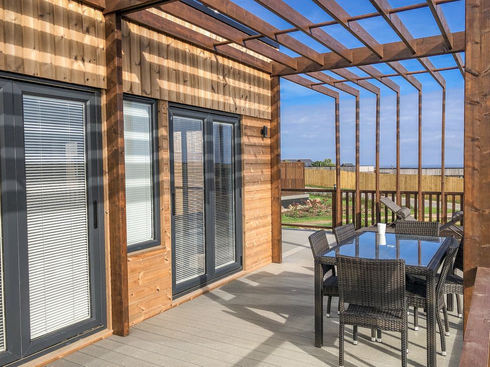 An outdoor patio with a dining table and chairs at Pentewan in Redruth