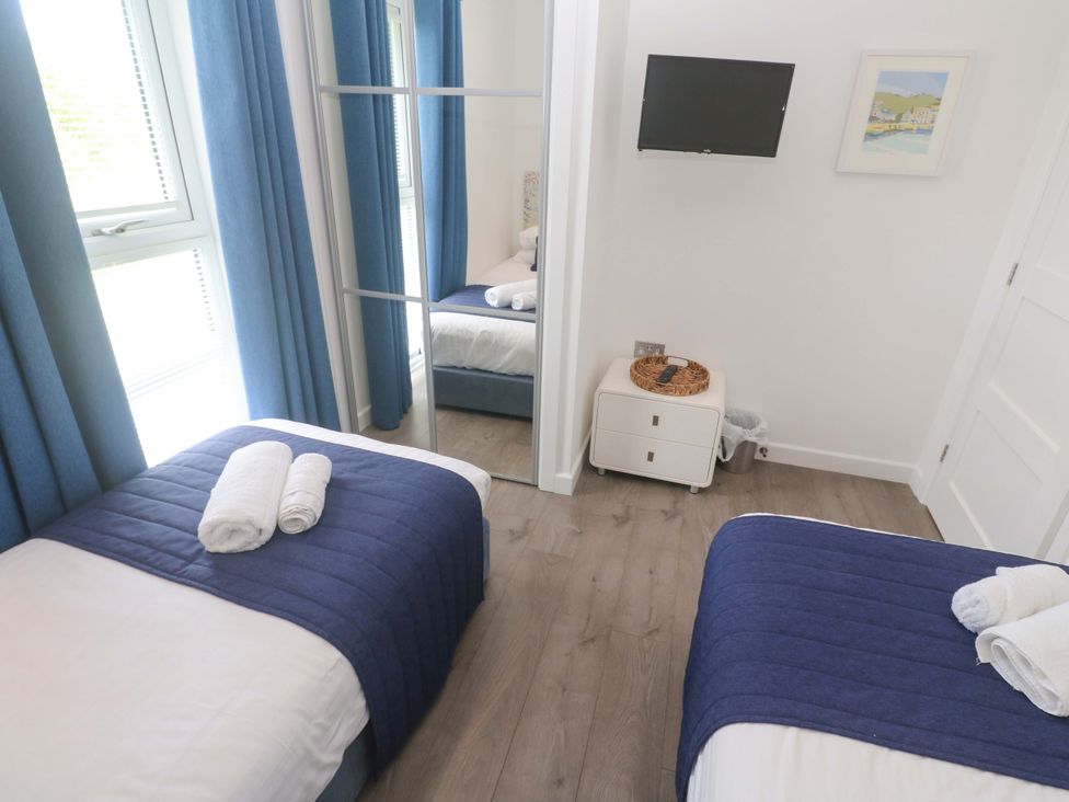 A bedroom with two beds, towels, a television and a mirror at Pentewan - 67 Portreath