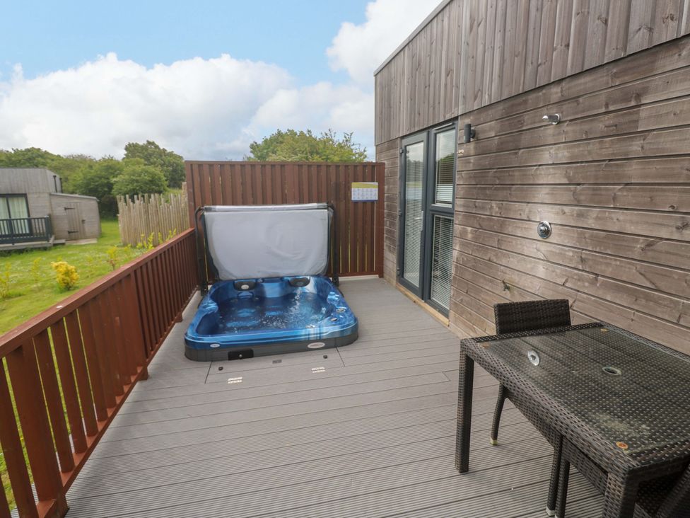 An outdoor area with a hot tub and a table at Pentewan - 67 in Portreath