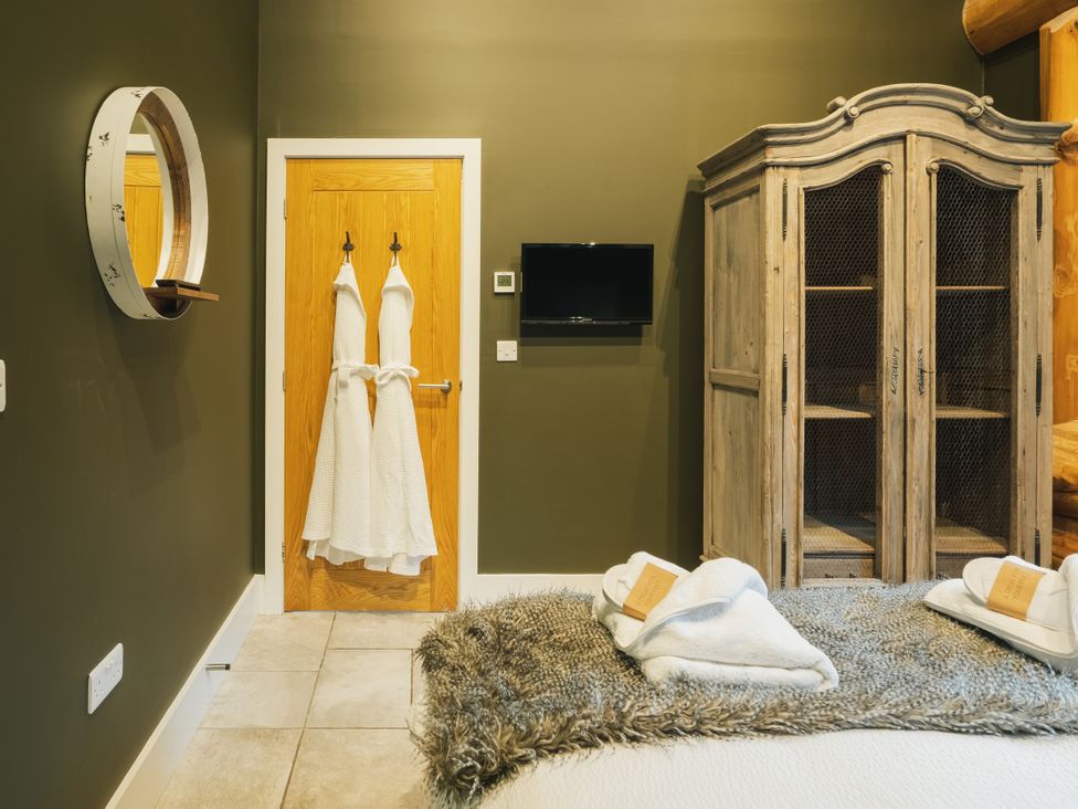 A bedroom with bathrobes hanging on a door and a cabinet at Bears Den Addingham