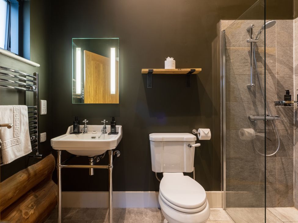 A bathroom with a sink, shower, toilet, and mirror at Bears Den in Addingham