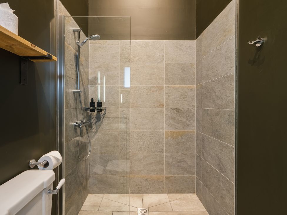 A shower area with tiles and a toilet at Bears Den in Addingham