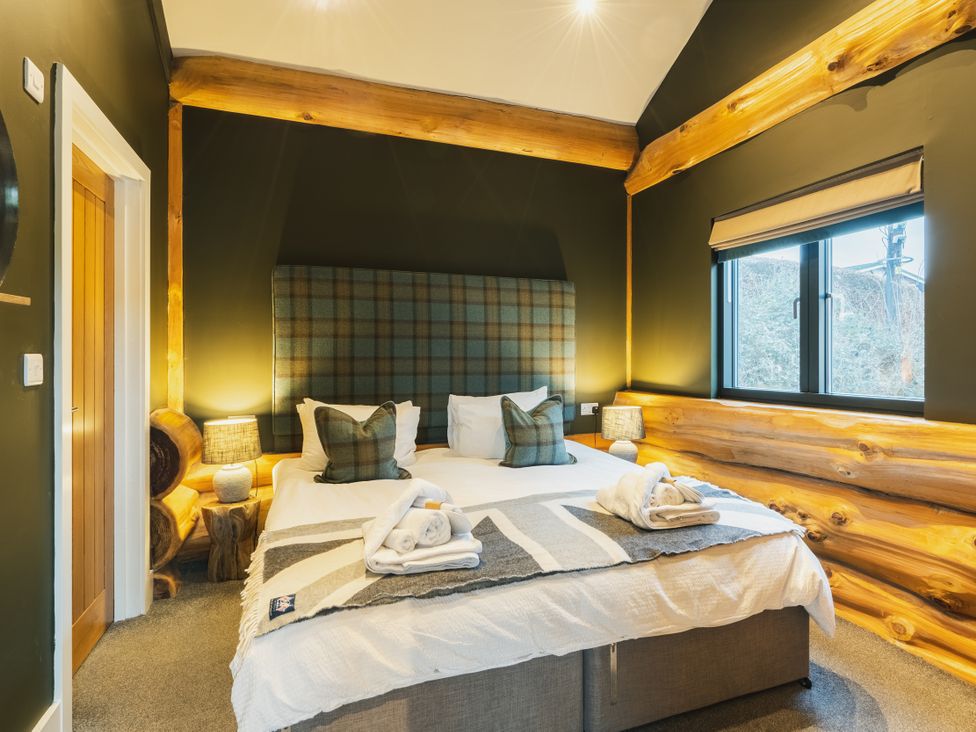 A bedroom with a bed and wooden walls at Bears Den in Addingham