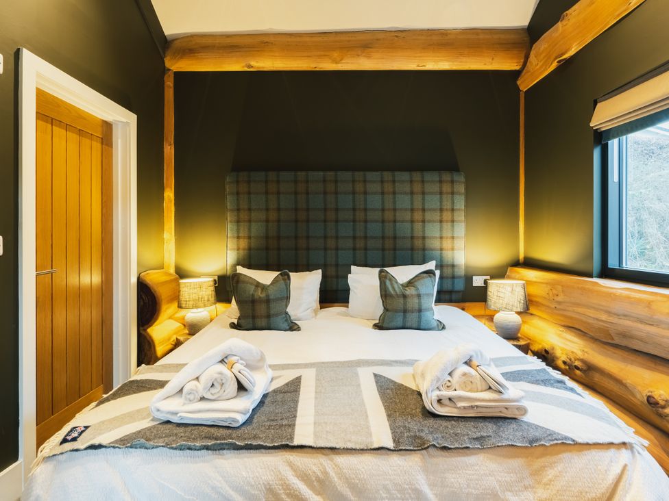 A bedroom with a bed, bedside lamps, and a window at Bears Den in Addingham