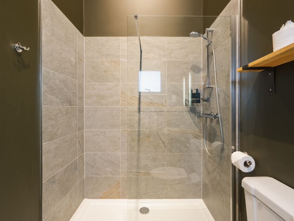 A shower area with a toilet and shelf at Bears Den in Addingham