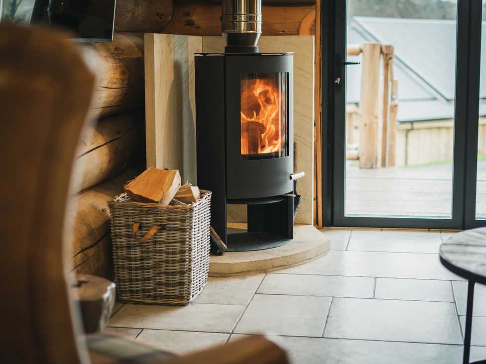 A living room with a wood stove and firewood basket at Keepers Cabin in Addingham