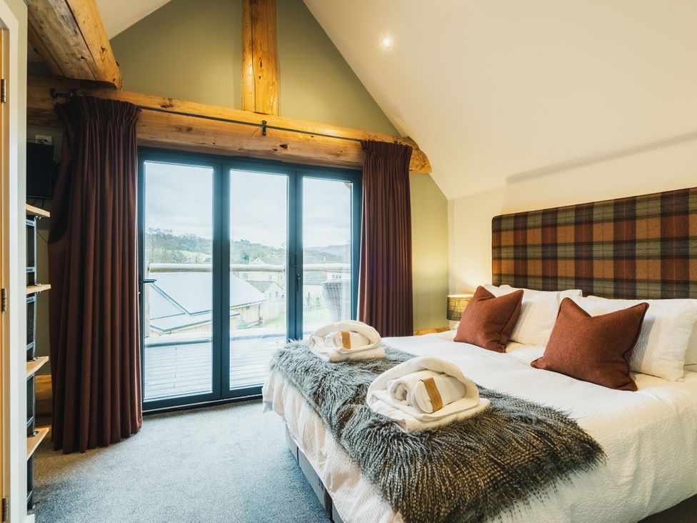 A bedroom with a bed and windows at Keepers Cabin in Addingham