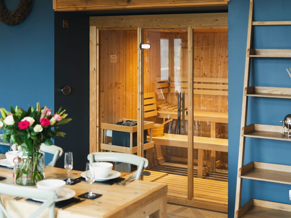 A dining room featuring a sauna and a table with flowers at The Farmhouse in Addingham