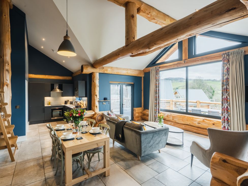 A living room with a kitchen area and large windows at The Farmhouse in Addingham